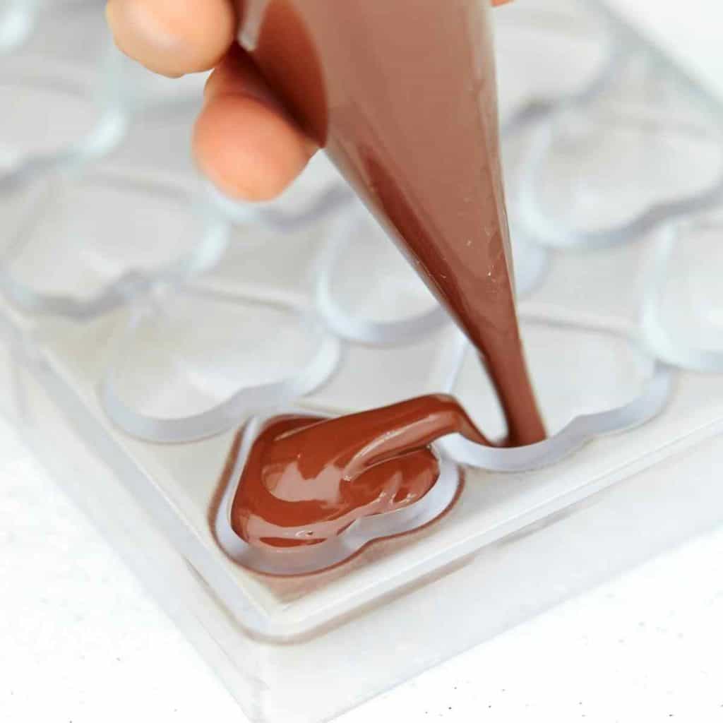 Allergy free chocolate being piped into heart molds