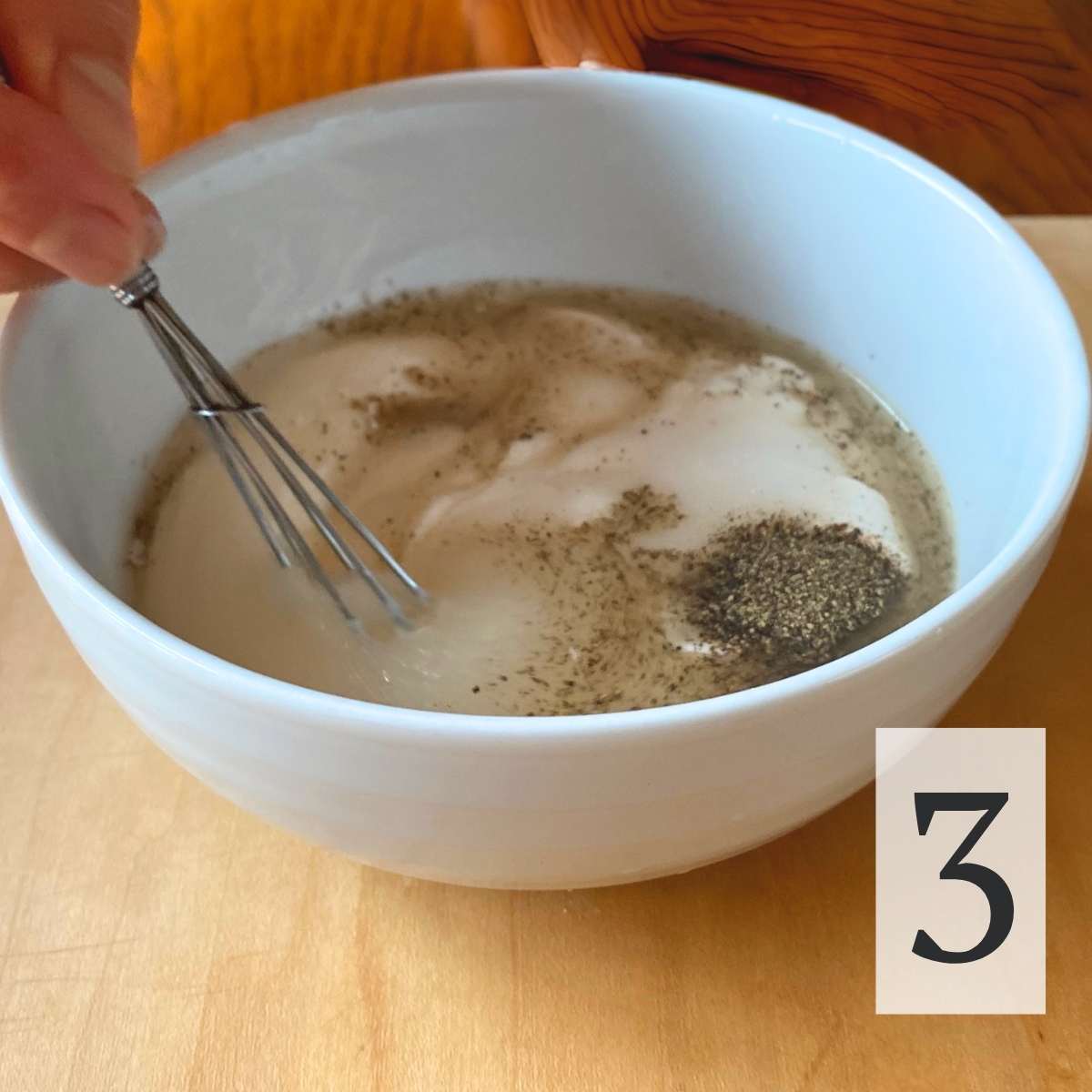 cabbage apple salad dressing ingredients in a bowl being mixed with a whisk