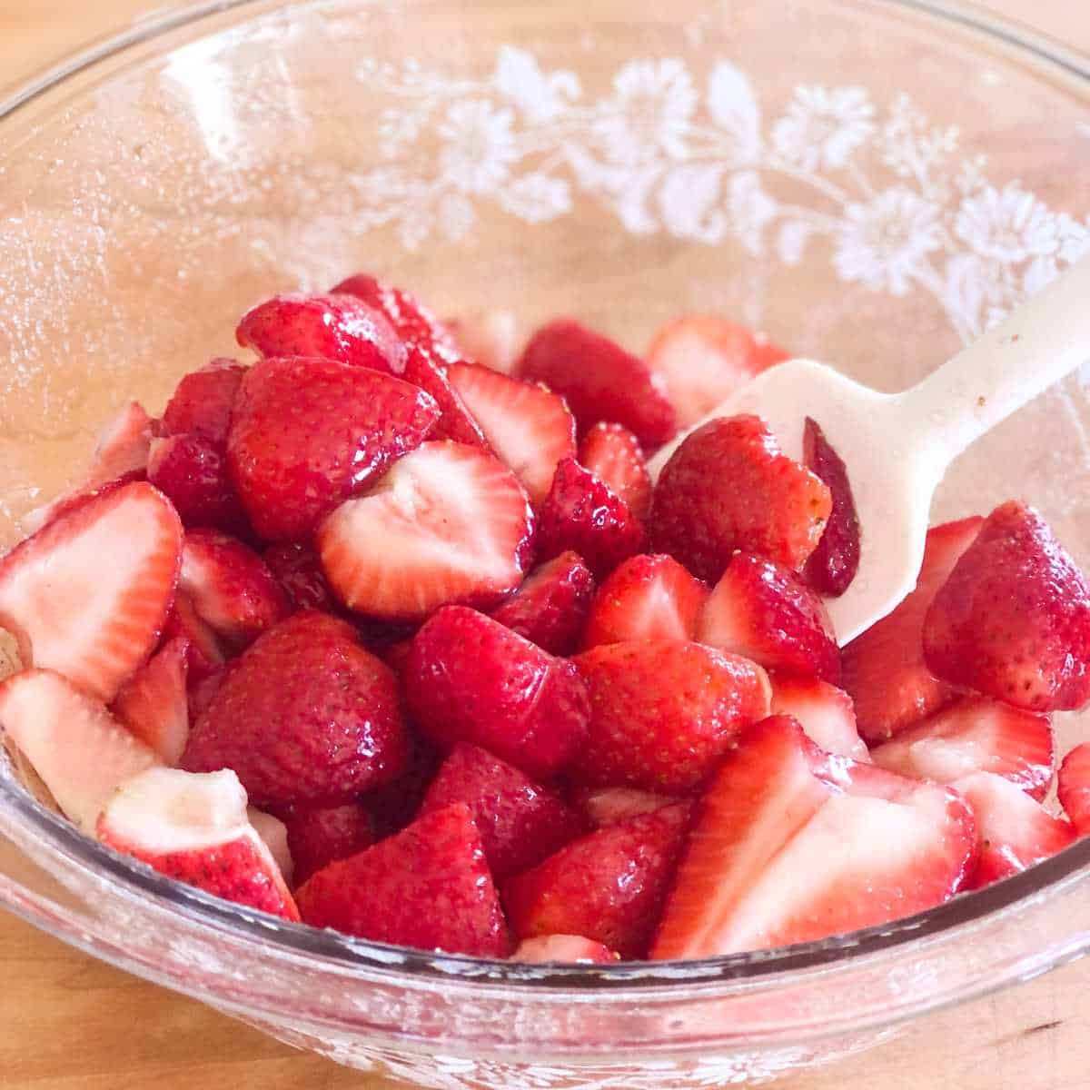strawberries in a large bowl coated in dissolved sugar