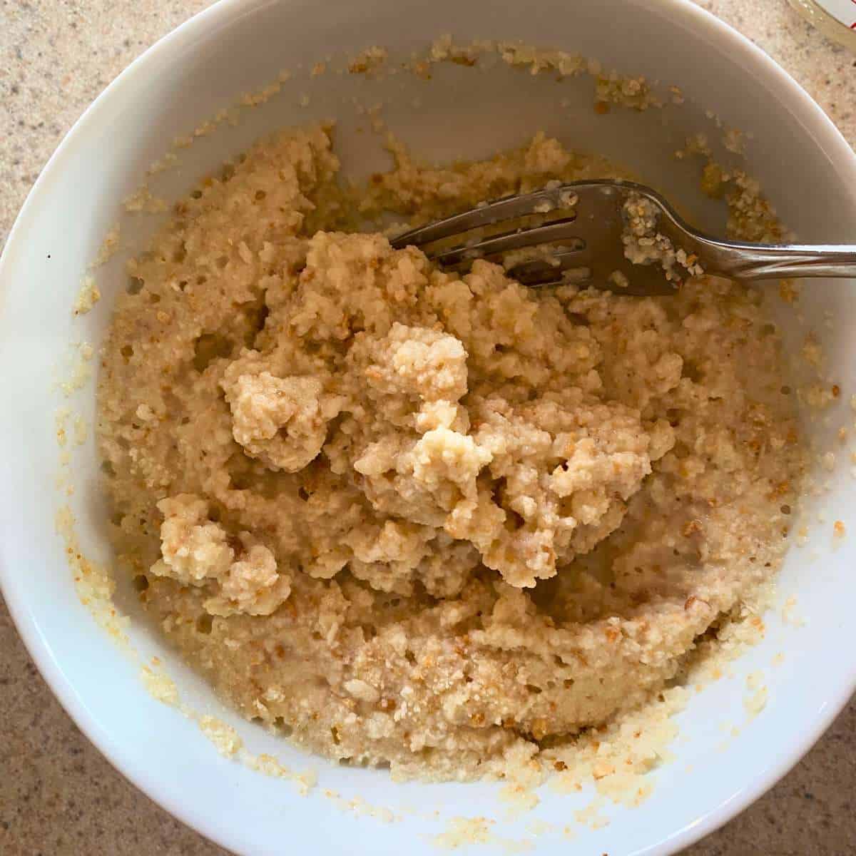 A mixture of gluten free breadcrumbs and dairy free milk in a bowl.