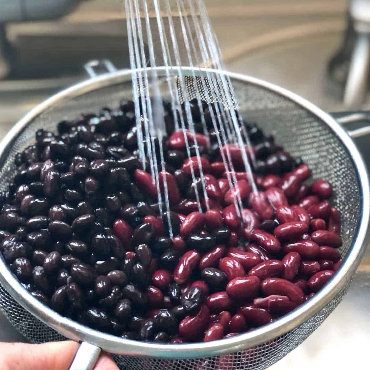 Kidney beans and black beans being rinsed.