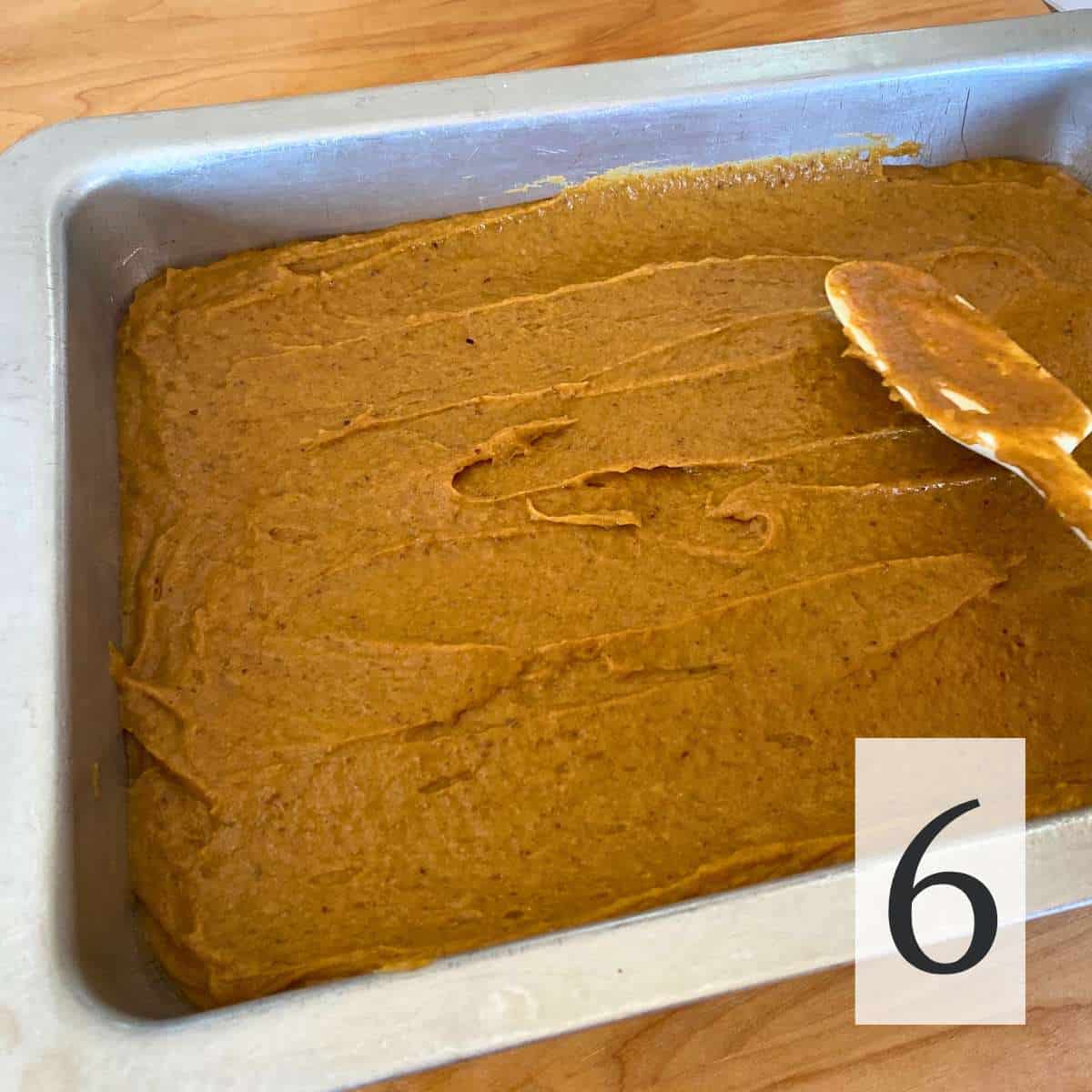 Gluten free pumpkin bar batter being spread in a 9 by 13 pan.