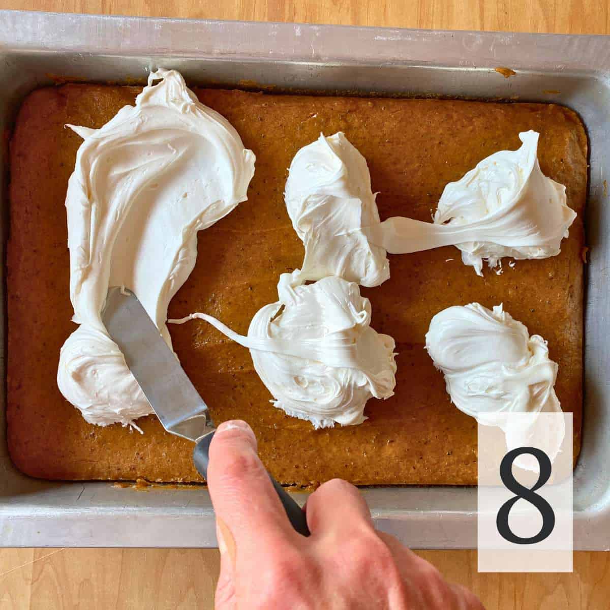 Frosting being spread over a pan of gluten free pumpkin bars.