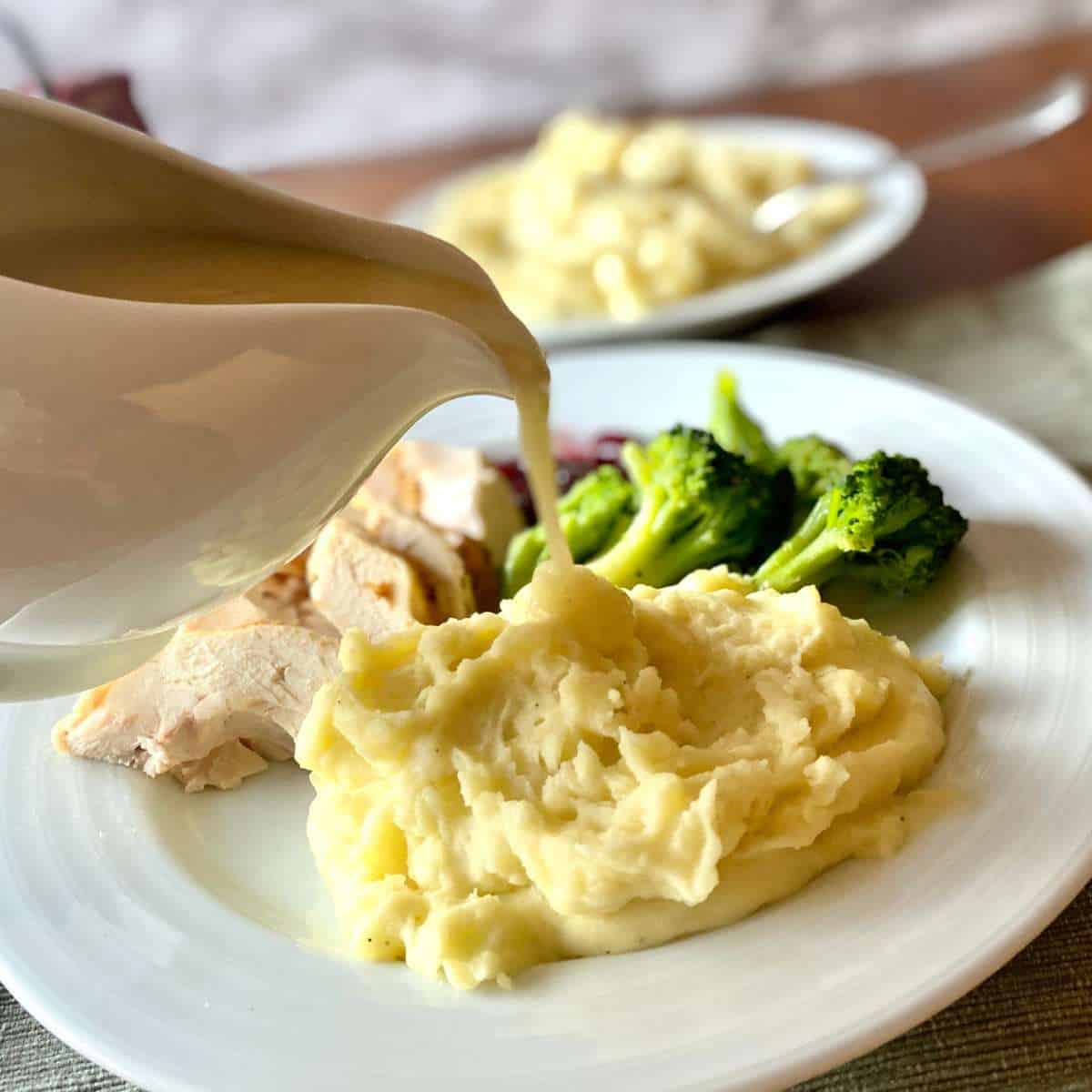 Gluten free turkey gravy being poured onto mashed potatoes.