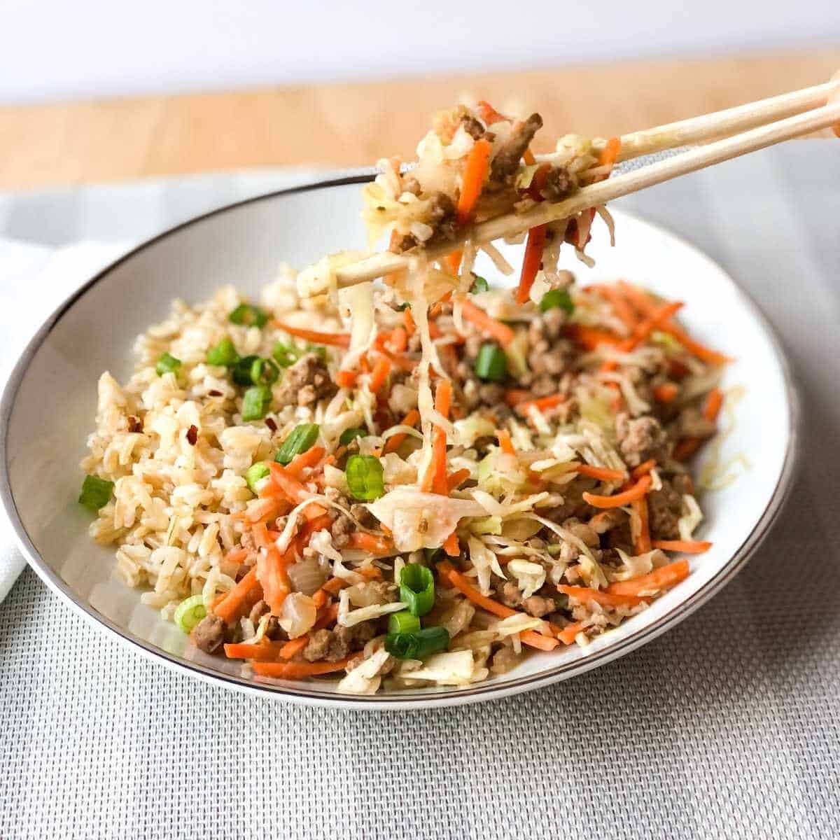 Inside out egg roll in a bowl being served with chopsticks.