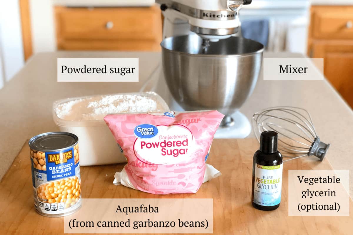 The ingredients needed for vegan royal icing including aquafaba (from canned garbanzo beans, powdered sugar, optional vegetable glycerin, and a stand mixer.